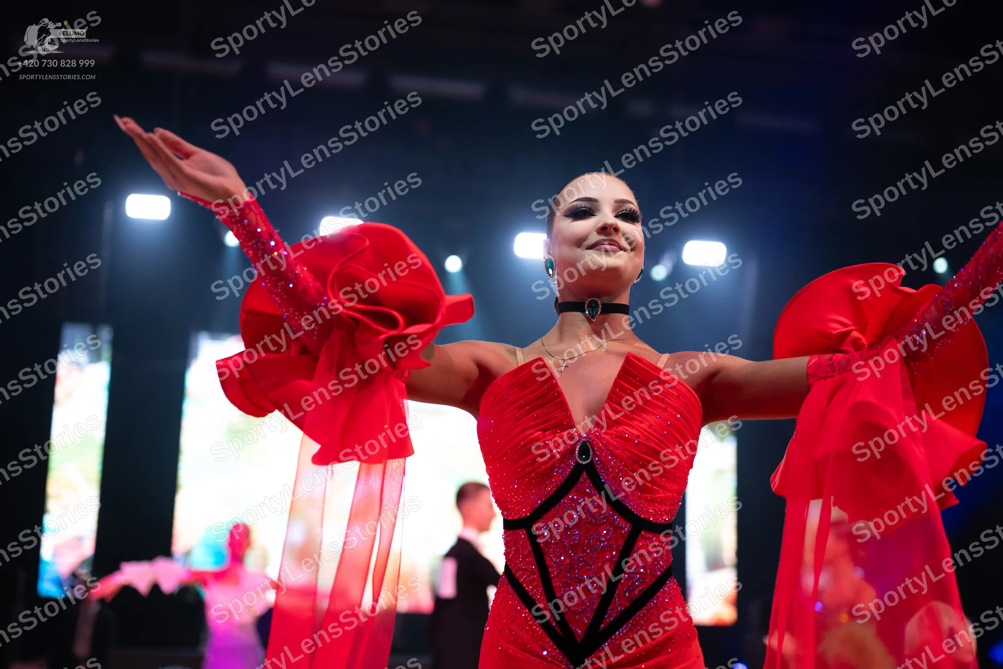 Dancesport competitor: Female dancer in foreground: red latin dress with a sequined bodice and black de