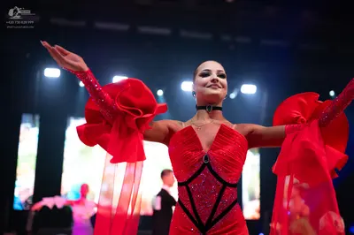Dancesport competitor: Female dancer in foreground: red latin dress with a sequined bodice and black de