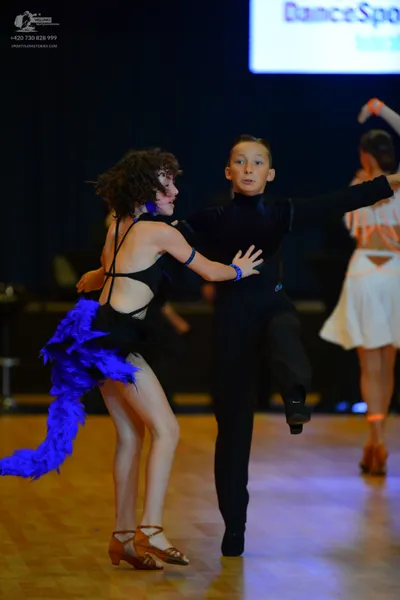 Dancesport competitor: Female dancer: black latin dance dress with thin straps and a large, vibrant blu