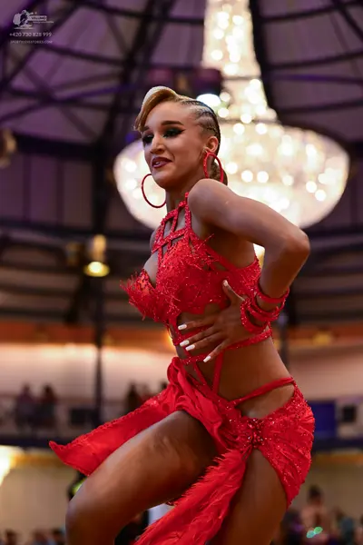 Dancesport competitor: Female dancer: red sequined Latin dance dress with cutouts and matching armbands