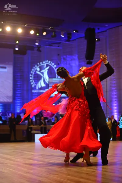 Dancesport competitor: Female dancer: red latin dress with flowing fabric and floral details
