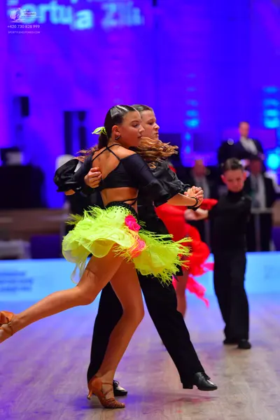 Dancesport competitor: Female dancer: black Latin dance top with long sleeves and a neon yellow/green s