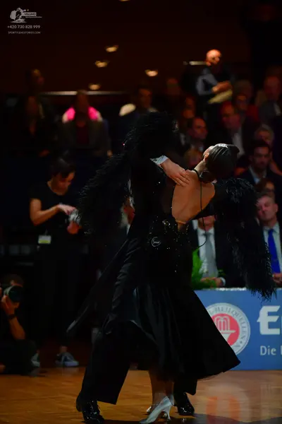 Dancesport competitor: Female dancer: black ballgown with large black feather accents