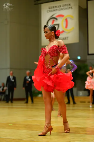 Dancesport competitor: Female dancer: red Latin dress with a sequined bodice and a multi-layered ruffle