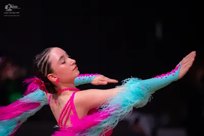 Dancesport competitor: Female dancer: bright pink and light turquoise Latin dance dress with feathery t