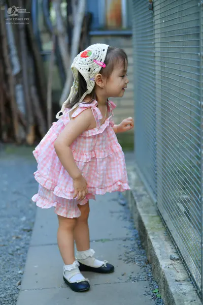 Dancesport competitor: Female dancer: pink and white checkered sleeveless ruffled dress, white lace hea