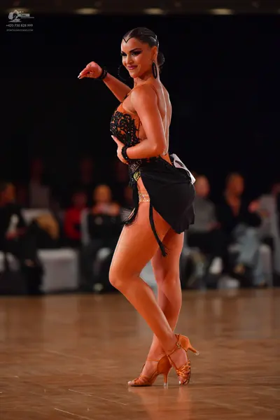 Dancesport competitor: Female dancer: black Latin dance costume with a black lace or sequin bodice and 