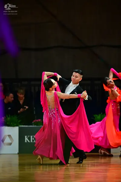 Dancesport competitor: Central female dancer: bright pink ballroom gown with extensive silver sequin an