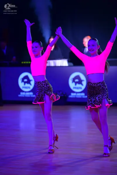 Dancesport competitor: Both dancers: matching bright pink long-sleeved crop tops and leopard-print skir