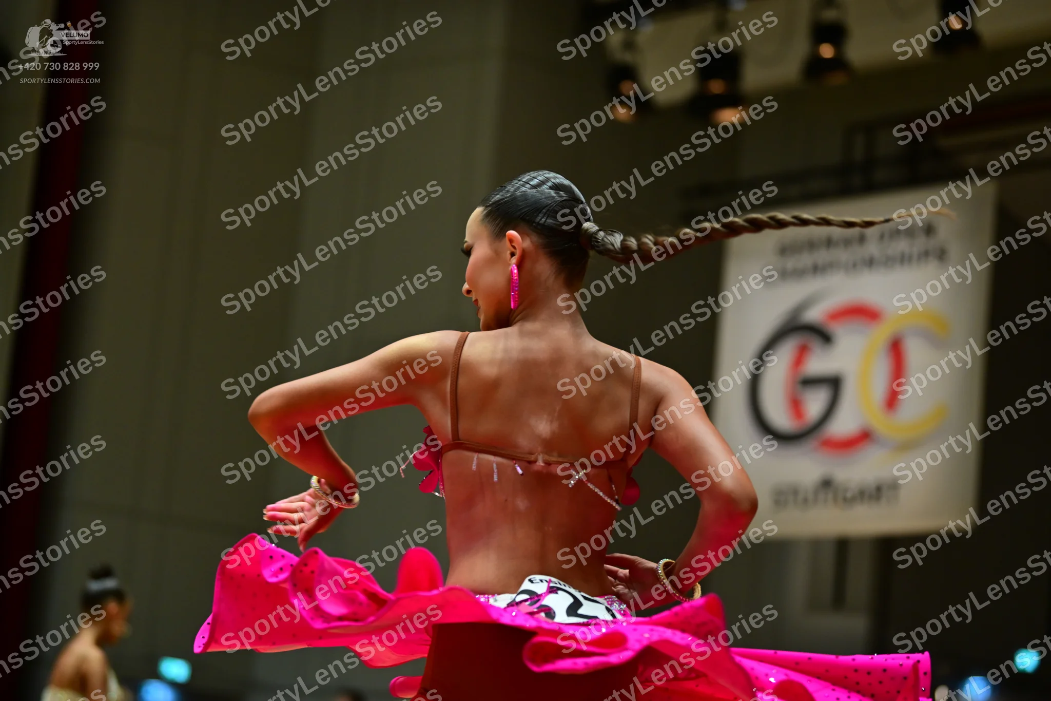 Dancesport competitor: Female dancer in foreground: bright pink Latin dance costume with a black and wh
