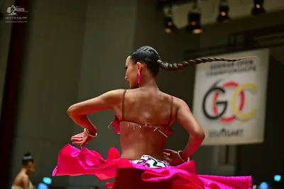 Dancesport competitor: Female dancer in foreground: bright pink Latin dance costume with a black and wh