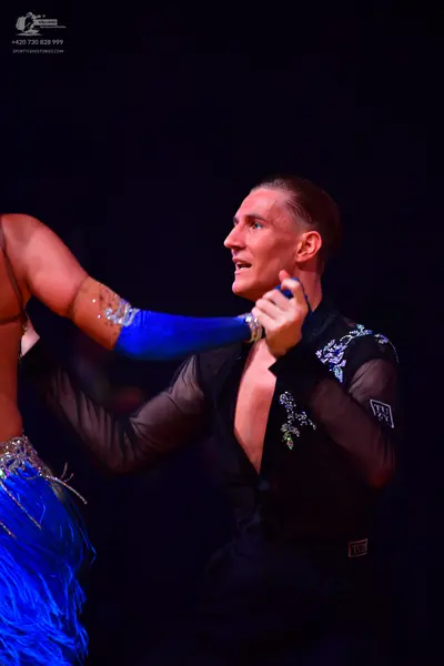 Dancesport competitor: Male dancer: black long-sleeved Latin top with sheer sleeves and silver sequin e