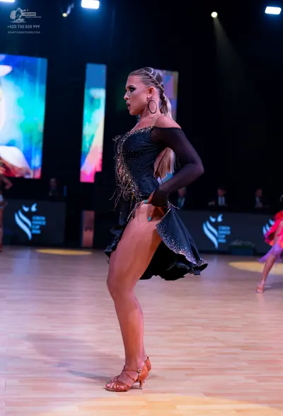 Dancesport competitor: Female dancer (center): black latin dress with sequins and a long black sleeve, 