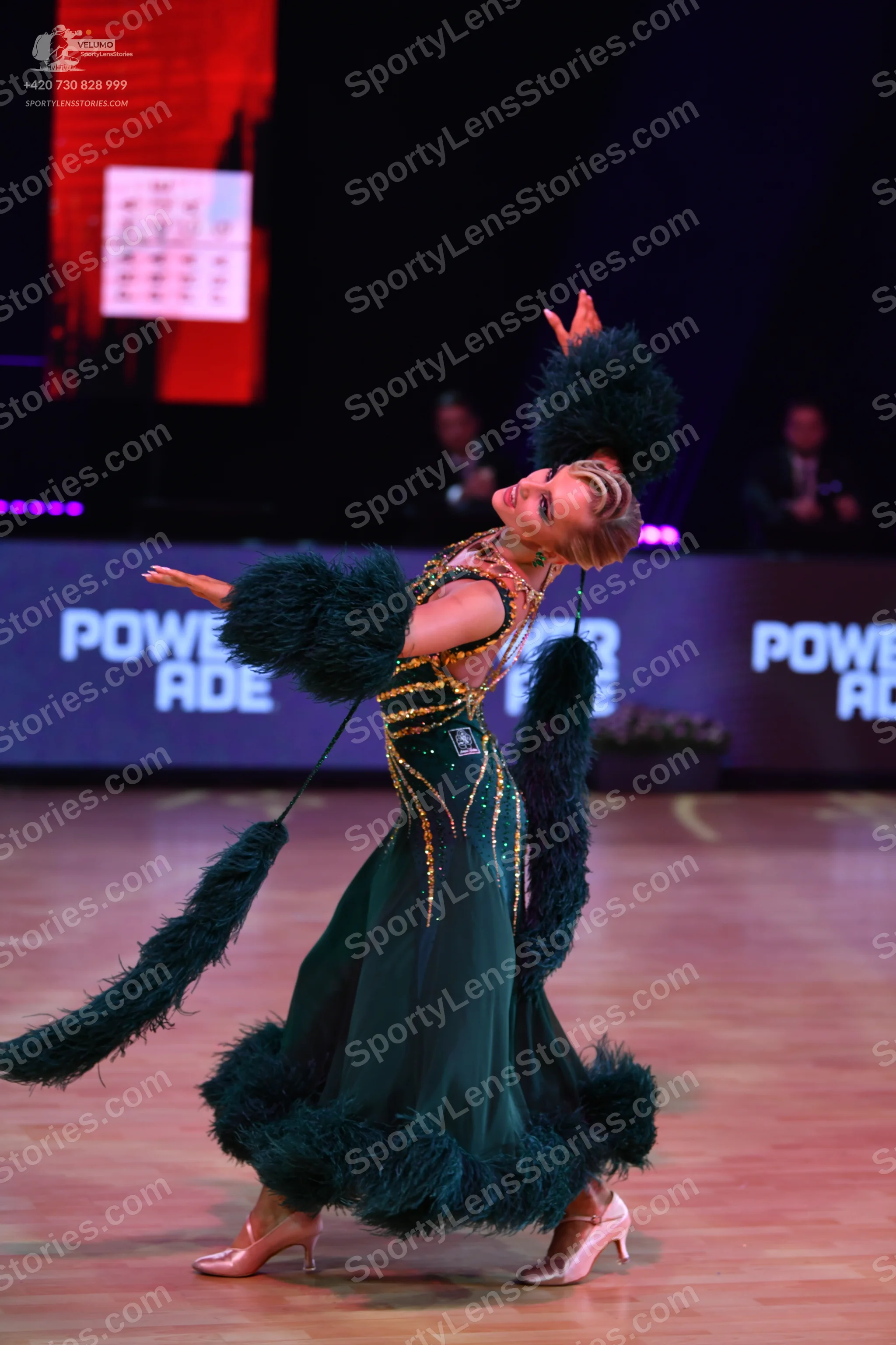 Dancesport competitor: Female dancer: dark green ballgown with gold sequin embellishments and large dar