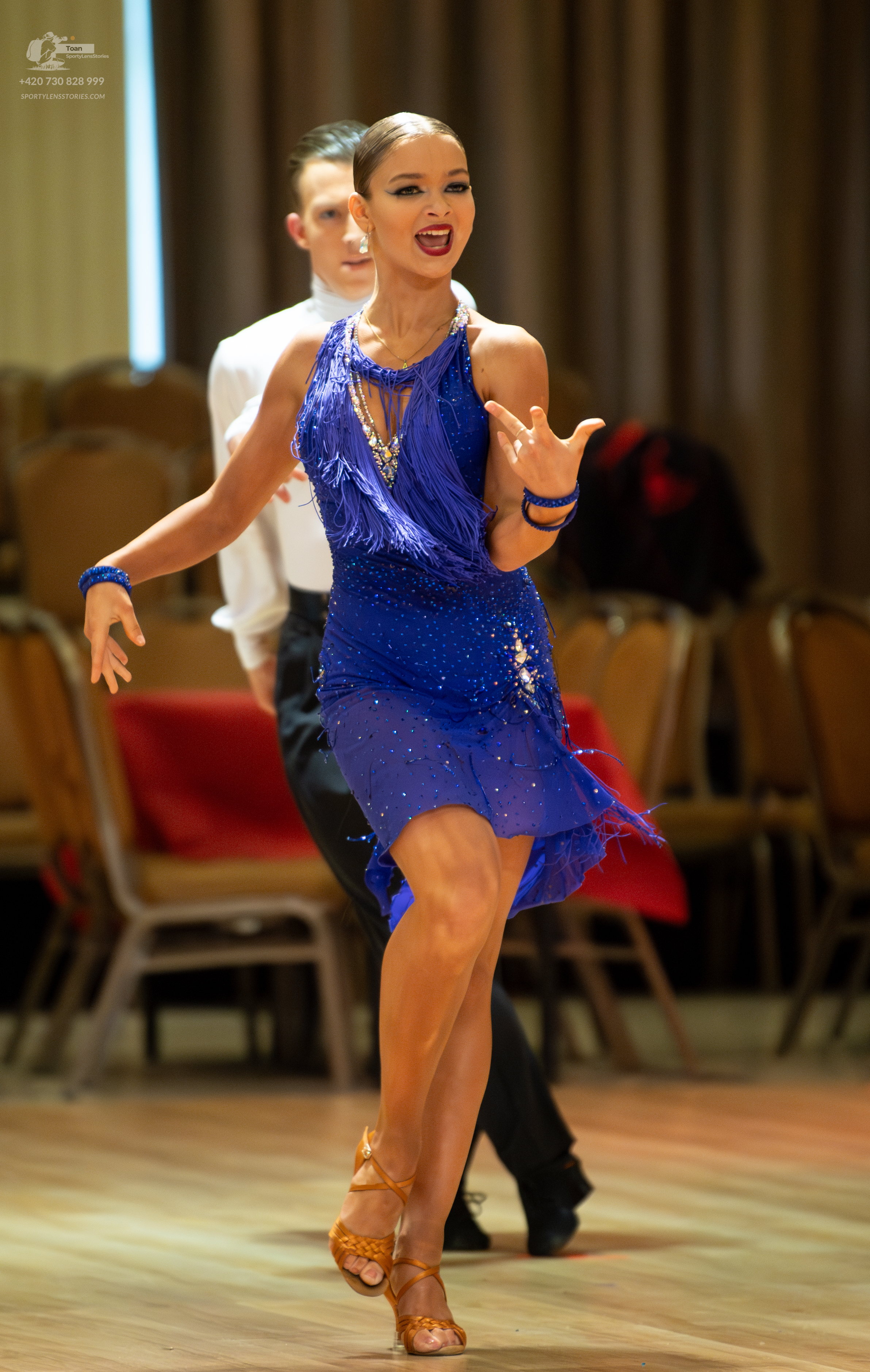 Dancesport competitor: Female dancer: blue Latin dress with fringe and sequins, and blue wristbands