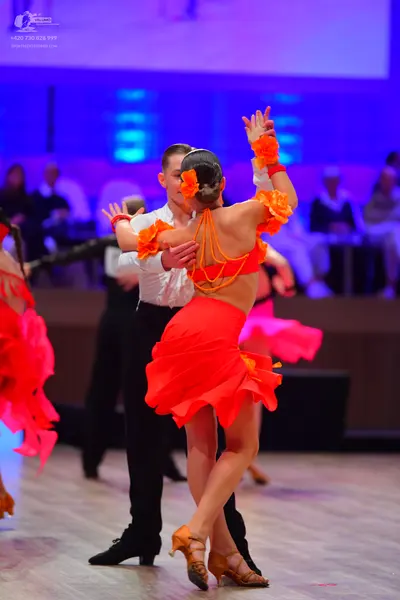 Dancesport competitor: Female dancer: orange Latin dance outfit consisting of a top with hanging orange