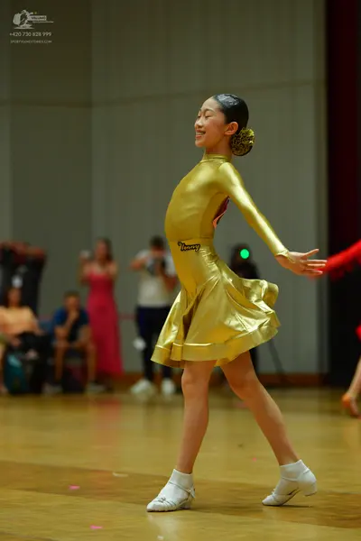 Dancesport competitor: Female dancer: gold latin dress with long sleeves, made of a metallic-looking fa