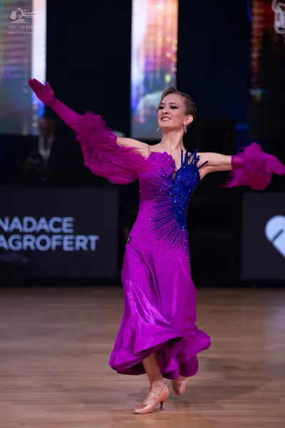 Dancesport competitor: Female dancer: magenta satin ballroom dress with a dark blue sequined bodice and