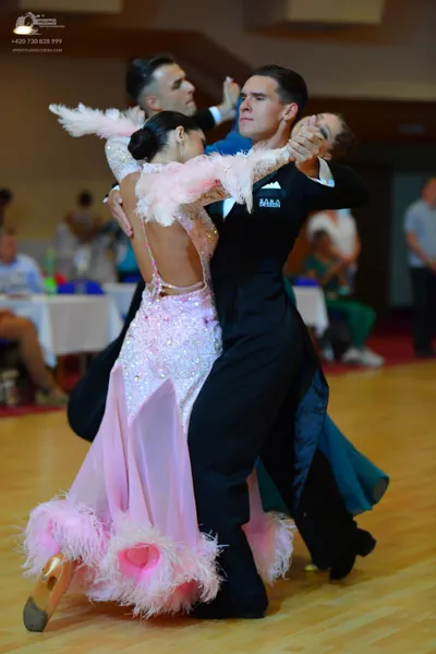 Dancesport competitor: Female dancer in foreground: light pink dance dress with a sequined bodice, larg
