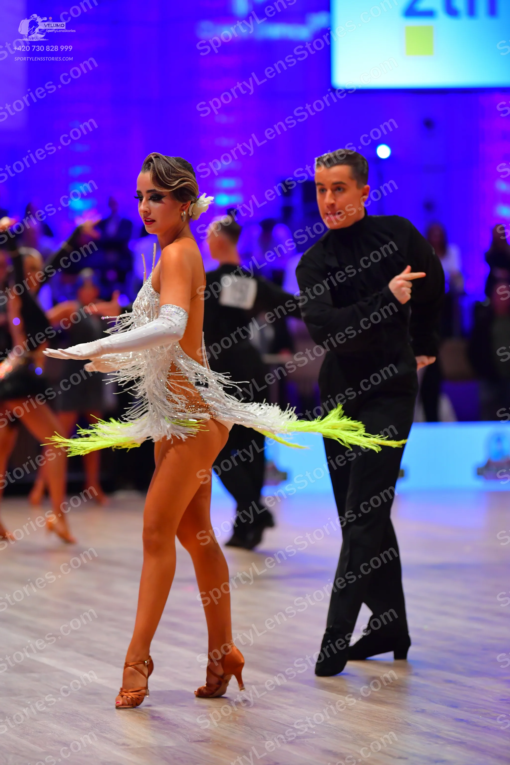 Dancesport competitor: Female dancer: white Latin dance dress with sequins and long white fringe, and l