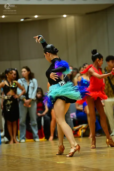 Dancesport competitor #70: Female dancer: black long-sleeved latin dress with a vibrant teal, blue, and pur