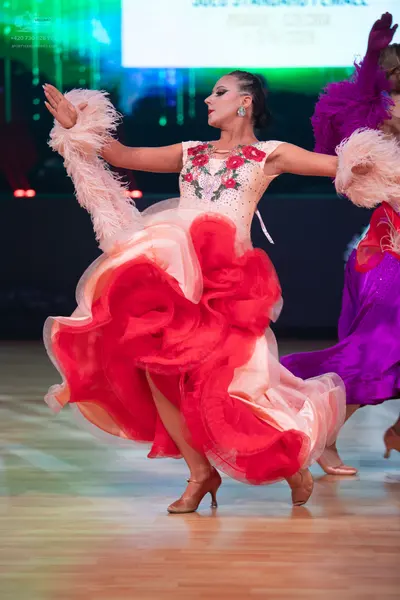 Dancesport competitor: Female dancer: white bodice with red and pink floral embroidery, featuring a vol