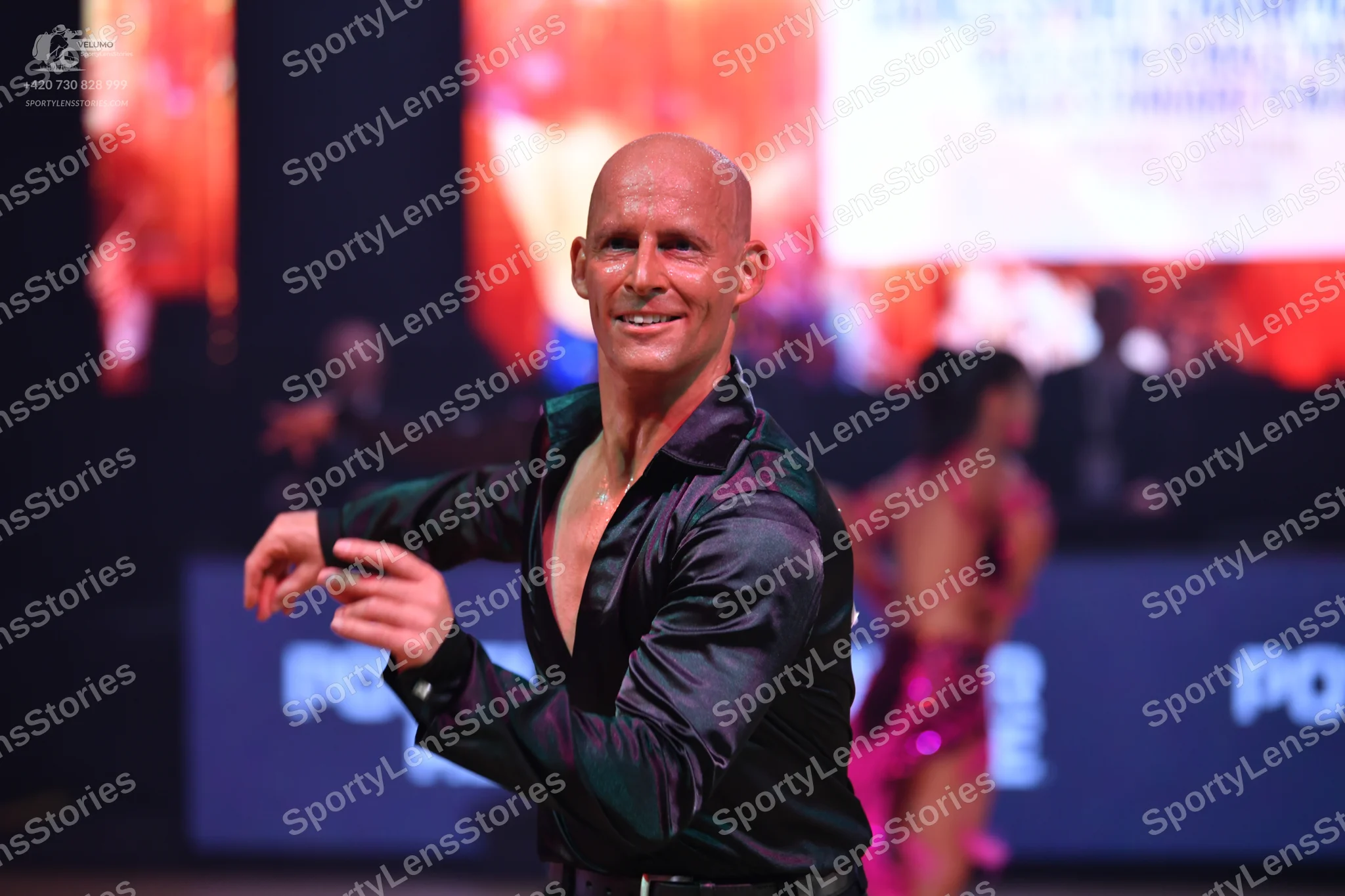 Dancesport competitor: Male dancer: black satin-like long-sleeved shirt, unbuttoned at the chest, and b