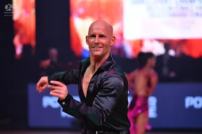 Dancesport competitor: Male dancer: black satin-like long-sleeved shirt, unbuttoned at the chest, and b