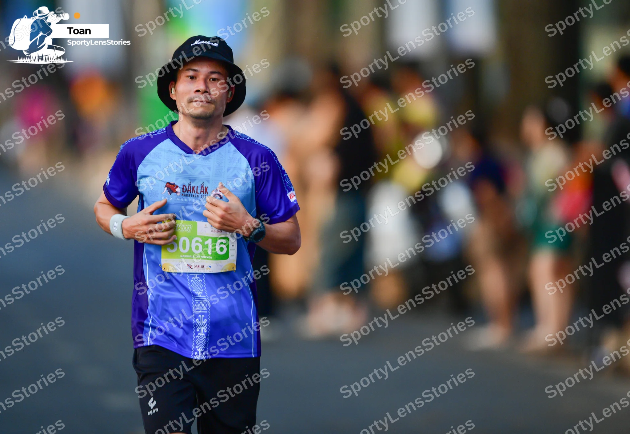 Marathon runner #0616: Runner 1: blue and light blue jersey, black shorts, black bucket hat, white wris