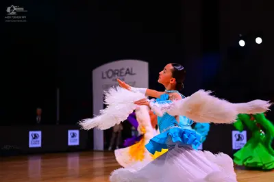 Dancesport competitor: Main female dancer: blue and white ballroom dress with large, white, fluffy arm 