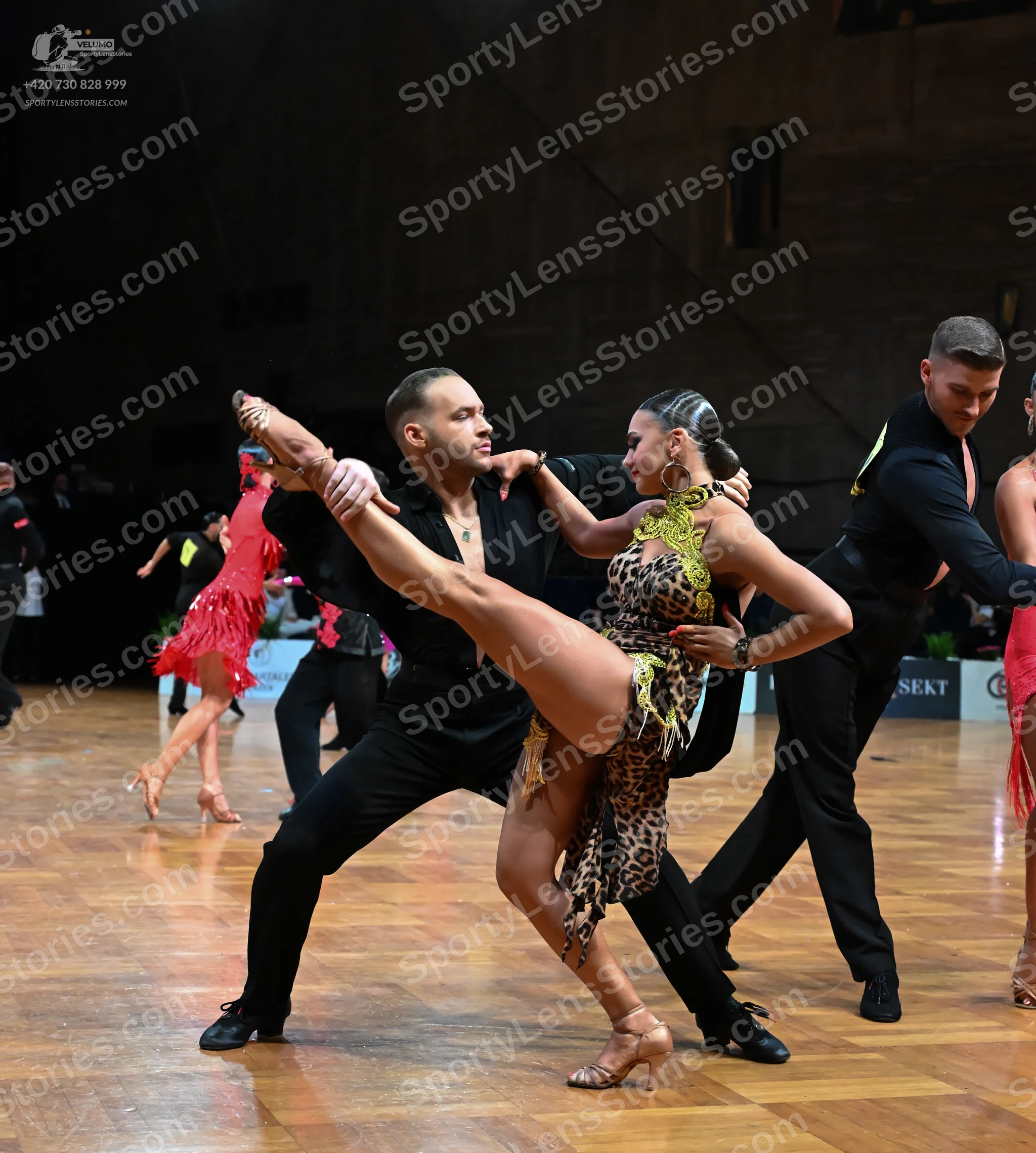 Dancesport competitor: Male dancer in foreground: black long-sleeved shirt and black trousers