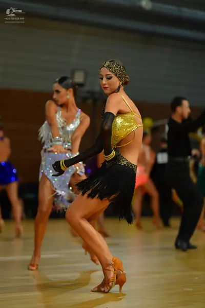 Dancesport competitor: Female dancer 1: gold sequin latin dance top, black fringed skirt, long black sl