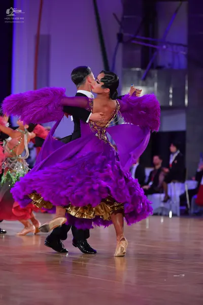Dancesport competitor: Female dancer: large, voluminous purple Latin dance dress with layers of ruffled