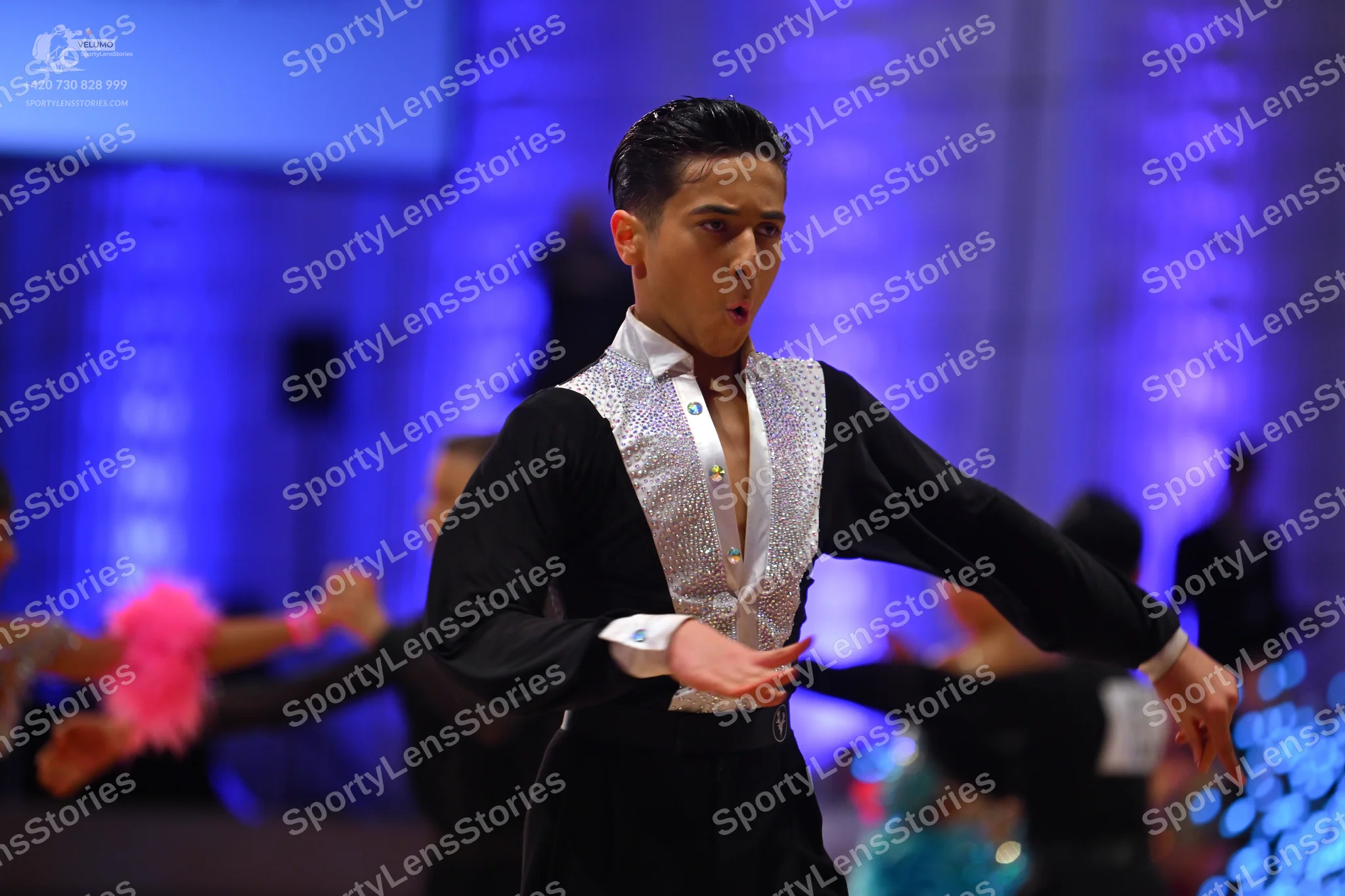Dancesport competitor: Male dancer in foreground: black long-sleeved shirt with a white/silver sequined