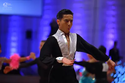 Dancesport competitor: Male dancer in foreground: black long-sleeved shirt with a white/silver sequined