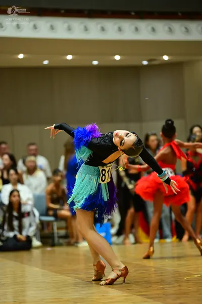 Dancesport competitor #81: Female dancer: black Latin dance dress with layers of blue, teal, and purple fri