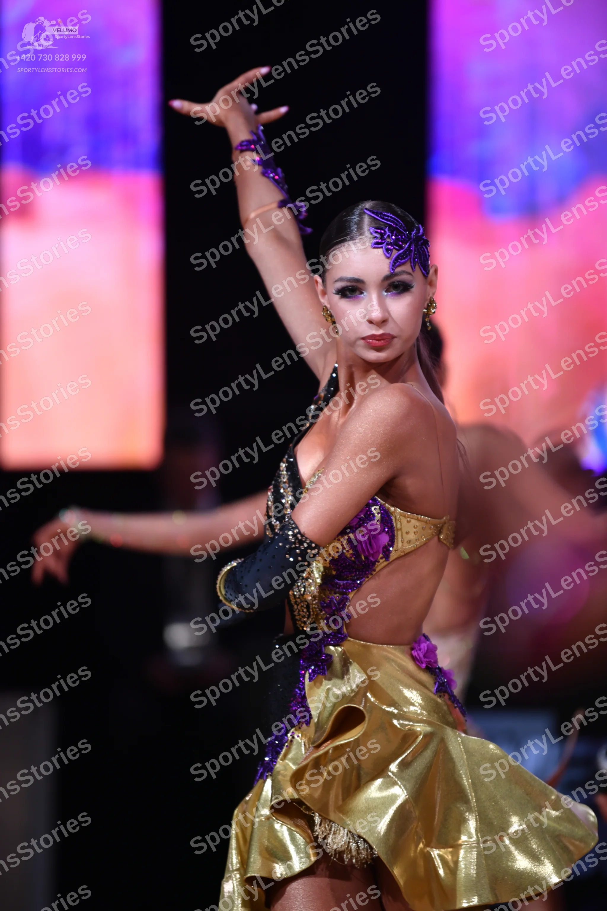 Dancesport competitor: Female dancer: gold, purple, and black latin dance costume with a metallic gold