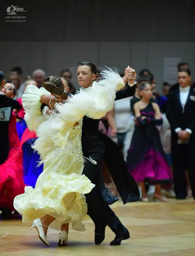 Dancesport competitor: Main female dancer: cream-colored, voluminous ballroom dress with large ruffled,
