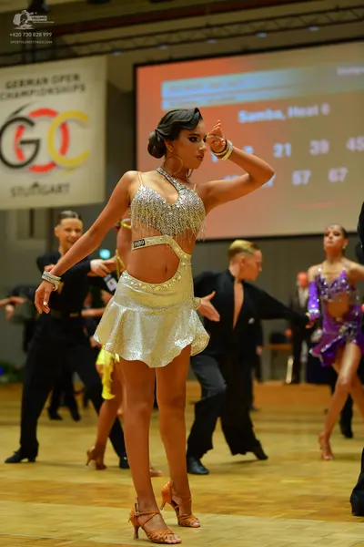Dancesport competitor: Female dancer (foreground): silver/champagne sequined Latin dress with a cut-out