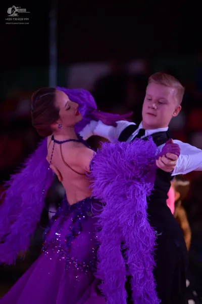 Dancesport competitor: Female dancer: purple backless latin dress decorated with sequins and large purp
