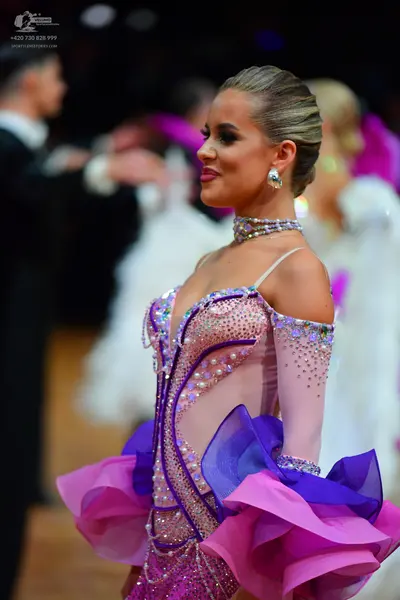 Dancesport competitor: Female dancer: Light pink Latin dress with purple and blue ruffled fabric, heavi