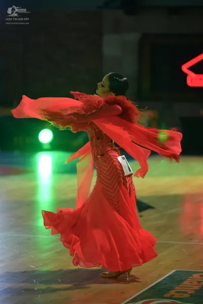 Dancesport competitor: Female dancer: long, flowing red ballroom dress with dramatic, voluminous sleeve