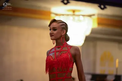 Dancesport competitor: Female dancer: red latin dress with sequins and fringe, featuring a strappy desi