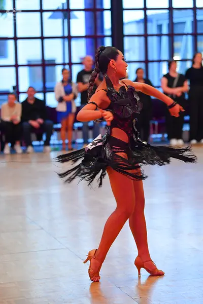 Dancesport competitor: Female dancer: black latin dress with a shiny bodice and a skirt featuring long,