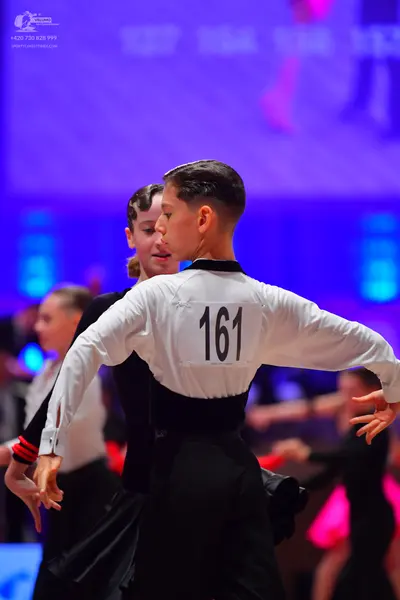 Dancesport competitor: Male dancer: white long-sleeved shirt with a black waistband and black trousers