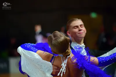 Dancesport competitor: Female dancer: blue and white dress with large blue feather accents and silver/w