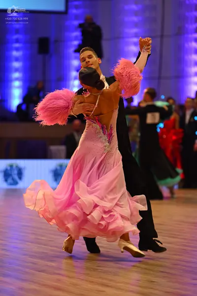 Dancesport competitor: Female dancer: pink ballgown with a voluminous, multi-layered ruffled skirt, a s