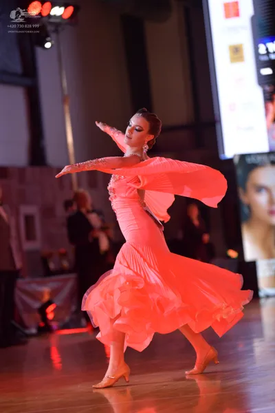 Dancesport competitor: Female dancer: pink ballroom dress with a full, ruffled skirt and long sleeves