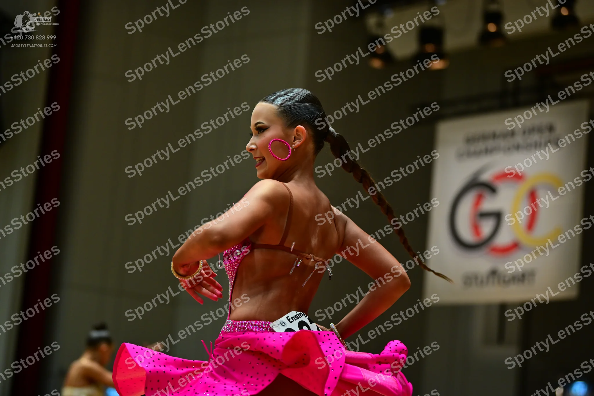 Dancesport competitor: Female dancer: bright pink Latin dance dress with sequins and a flared, layered 