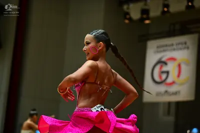 Dancesport competitor: Female dancer: bright pink Latin dance dress with sequins and a flared, layered 